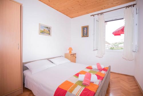 ein weißes Schlafzimmer mit einem Bett und einem Fenster in der Unterkunft Apartments Salis in Pag