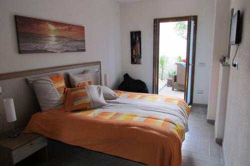 - une chambre avec un grand lit et une couverture orange dans l'établissement Apartment - La dolce vita - where dreams come true, à Valledoria