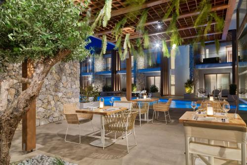 a restaurant with tables and chairs and a tree at Utopia Blu Hotel in Tigaki
