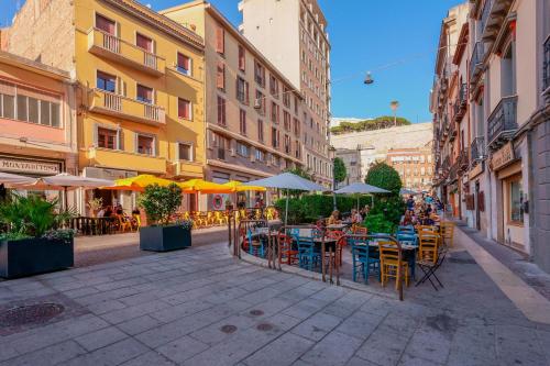 una calle vacía con mesas, sillas y sombrillas en Le Suite Sul Corso, en Cagliari