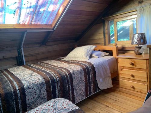 a bedroom with a bed and a dresser in a cabin at Colinas de Mindo in Mindo