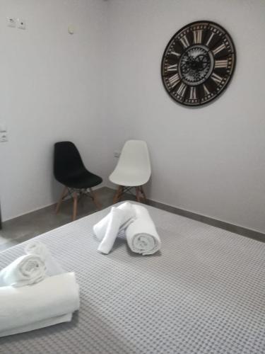 a room with a clock and towels on a bed at Aiolos Blu Luxury Apartments in Nea Roda