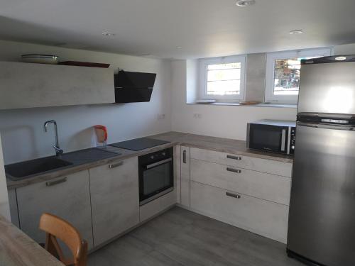 une cuisine avec des armoires blanches et un réfrigérateur en acier inoxydable dans l'établissement T2 CONLEAU à Vannes 200 mètres de la mer, à Vannes