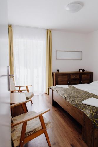 a bedroom with a bed and a chair and a window at Nyírfa Apartman in Vonyarcvashegy