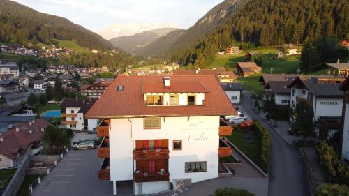 a building with a red roof in a village at Hotel Garni Walter in Ortisei