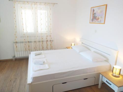 a white bedroom with a bed and a window at Apartments Antonio in Senj