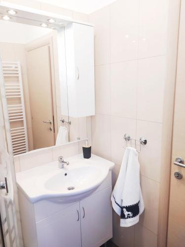 a white bathroom with a sink and a mirror at Apartments Antonio in Senj