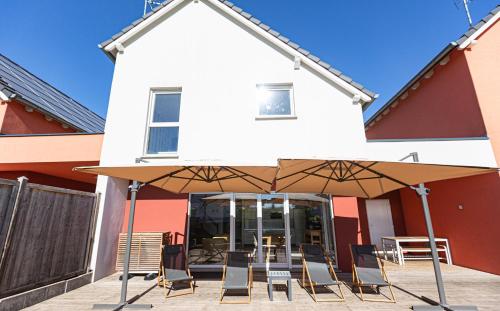 a group of chairs and umbrellas in front of a building at LES MAISONS SOLAIRES Contact O6614O9II9 Villa pour 15 pers maxi in Griesheim-près-Molsheim