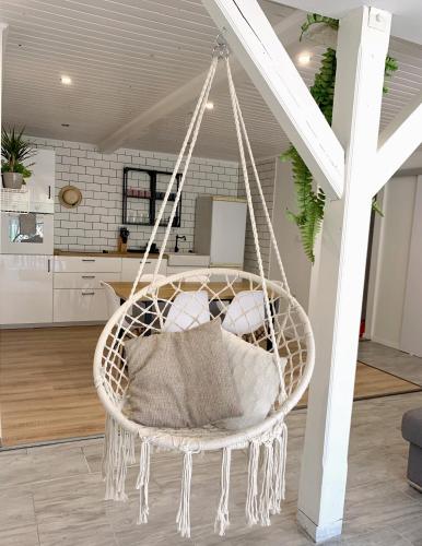 a hanging basket chair with pillows in a living room at Aranykert Apartmanok Vének in Vének