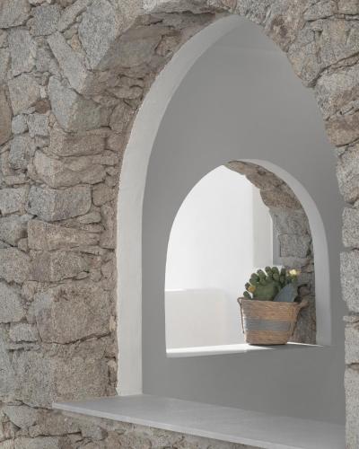 an archway with a cactus on a shelf in a stone wall at Mykonos Essence Adults Only in Ornos