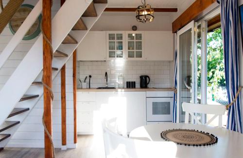 a kitchen with white cabinets and a spiral staircase at Domek całoroczny nad morzem Stegna Baltica in Stegna