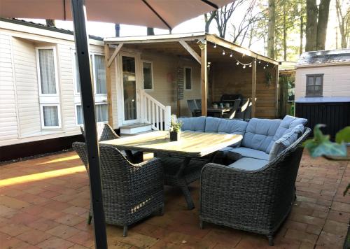 a patio with a table and chairs and an umbrella at Prachtige Luxe chalet op de Veluwe nabij Hoenderloo in Hoenderloo