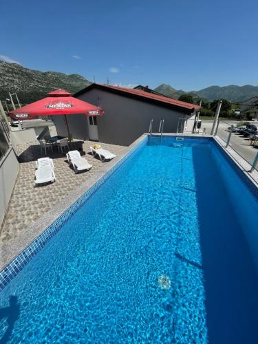 a large blue swimming pool with an umbrella and chairs at Ninkovic in Trebinje
