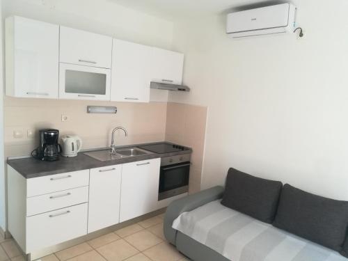 una cocina con armarios blancos y un sofá en una habitación en Apartments Vukas, en Lumbarda