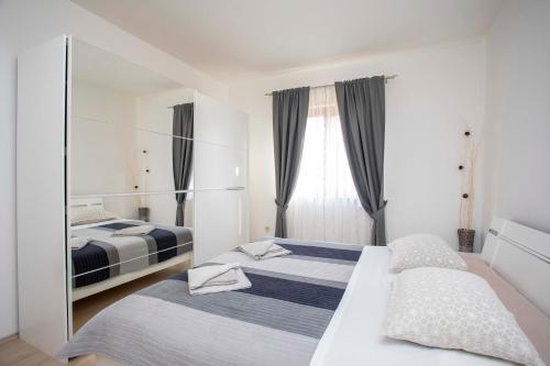 a bedroom with two beds and a mirror at Apartmani Marica in Plomin