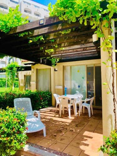 a patio with white tables and chairs under a pergola at VILLA PARA 5P 4A 1M dentro del Hotel a un lado del Krystal IXTAPA Con Playa WiFi in Ixtapa