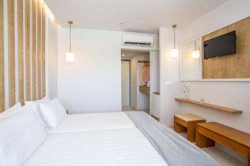 a bedroom with a white bed and a tv on a wall at Tsampika Hotel Faliraki in Faliraki