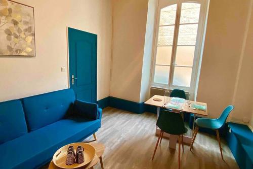 a living room with a blue couch and a table at Appartement de charme plein coeur de Moulins in Moulins