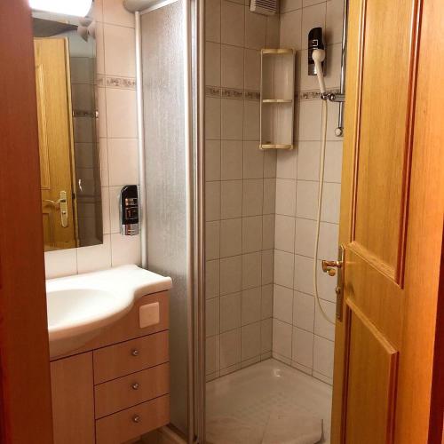 a bathroom with a shower and a sink and a mirror at Alpina in Leukerbad