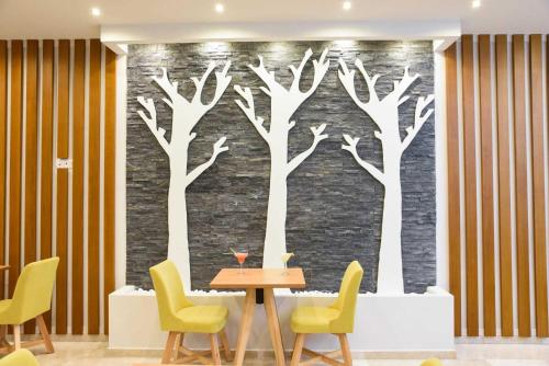 a wall mural of trees with a table and chairs at Tsampika Hotel Faliraki in Faliraki
