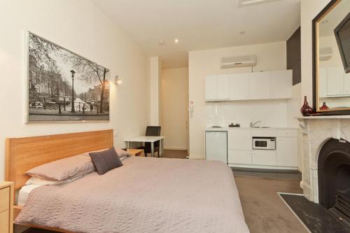 a bedroom with a large bed and a kitchen at Sixty Two On Grey Serviced Apartments in Melbourne