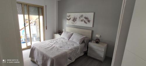een slaapkamer met een bed met witte lakens en een raam bij RELAX i SOL in Cambrils