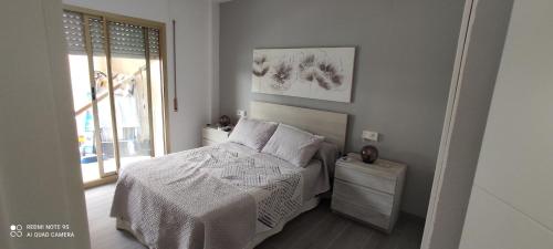 Un dormitorio con una cama con sábanas blancas y una ventana. en RELAX i SOL, en Cambrils