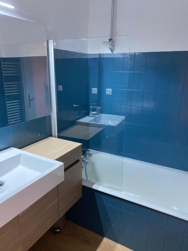 Un baño con lavabo, bañera y espejo. en Location studio plein centre Les Carroz, en Les Carroz d'Araches