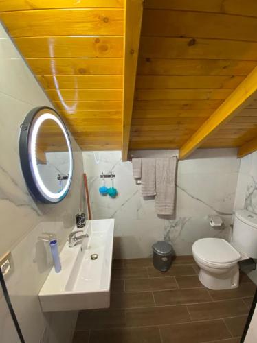 a bathroom with a sink and a toilet and a mirror at Bixhaku GuestHouse in Gjirokastër