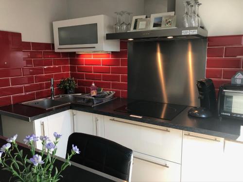 Il comprend une cuisine avec un évier et un mur en briques rouges. dans l'établissement appartement romantique tout confort 4 personnes, à Boulogne-sur-Mer