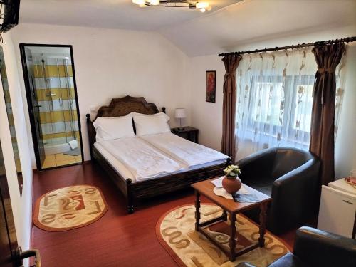 a bedroom with a bed and a chair and a table at Pensiunea Eden in Curtea de Argeş