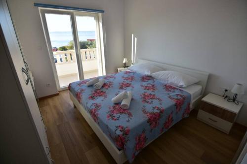 ein Schlafzimmer mit einem Bett mit einer Blumendecke und einem Fenster in der Unterkunft Villa Katarina - infinity pool with amazing view in Bol
