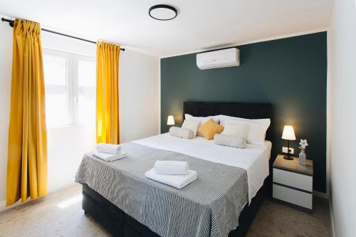 a bedroom with a large bed with yellow curtains at Villa Magna - seaside villa with pool and sauna in Trogir