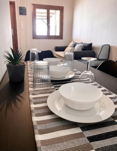 a table with white plates and wine glasses on it at Sea view in Artemis in Artemida