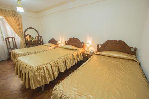 a bedroom with three beds with gold sheets at Hostal España in Sucre