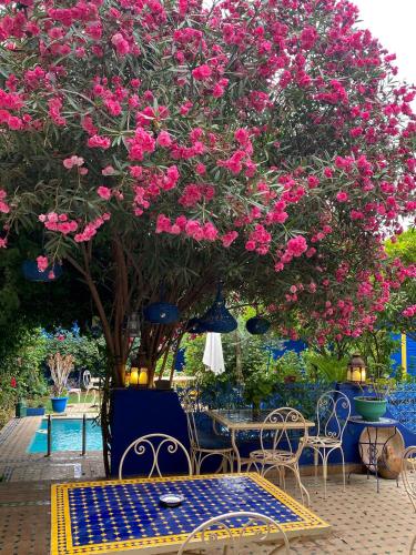 a table and chairs under a tree with pink flowers at Riad Jean Claude in Fez