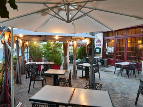 un patio extérieur avec tables, chaises et un parasol dans l'établissement Auberge de la marquise, à Arnac-Pompadour