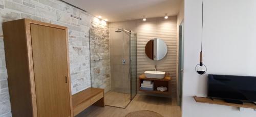 a bathroom with a shower and a sink and a television at Villa Tholos Crete in Kavoúsion