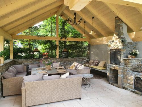 an outdoor patio with couches and a stone fireplace at Gorce Oasis in Szlembark