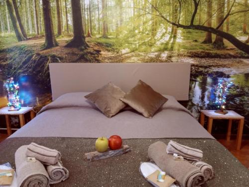 Una cama con manzanas y toallas y una pintura de un bosque en Montegrappa Fly on, en Crespano del Grappa