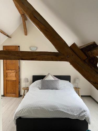 - une chambre avec un grand lit et des poutres apparentes dans l'établissement Gîte La Roche, à Reffuveille