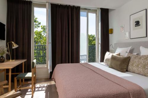 een slaapkamer met een bed, een bureau en een raam bij Le Petit Beaumarchais Hotel & Spa in Parijs