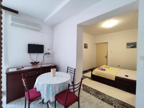 um pequeno quarto com uma mesa e cadeiras e uma cama em Apartmani Djedovic 2 em Petrovac na Moru