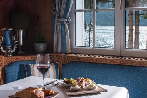 a table with a plate of food and a glass of wine at Via Salina - Hotel am See - Adults Only in Haldensee