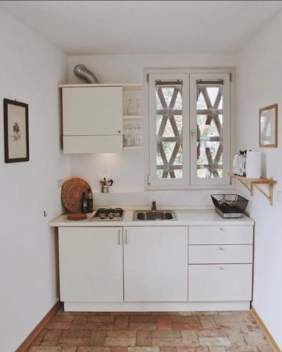 a white kitchen with a sink and a window at Casa Griunit in Capriva del Friuli