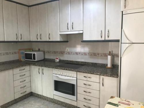 a kitchen with white cabinets and a white refrigerator at Apartamentos turísticos CHUS in A Coruña