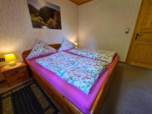 um quarto com uma cama com um edredão roxo em Appertment Bärenstein 2 em Gößweinstein