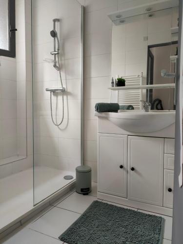 une salle de bain blanche avec une douche et un lavabo dans l'établissement Joli studio les pieds dans l eau avec place de Parking gratuite, à Bandol