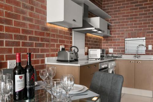a kitchen with a table with wine bottles and glasses at Easy Stay - The Vantage Rosebank in Johannesburg