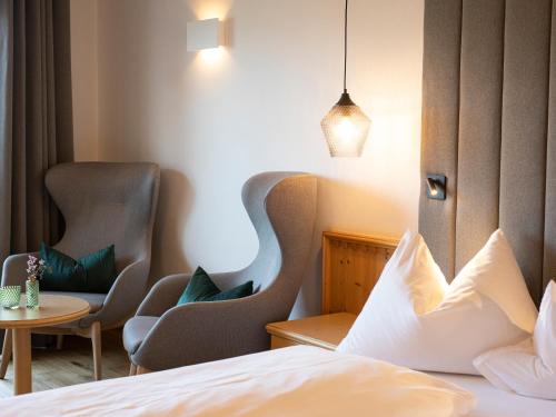 a hotel room with two chairs and a bed at Hotel Weingut Innerleiterhof in Schenna